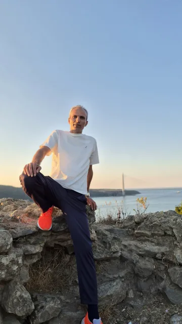 Galip Arduç'un İstanbul Beykoz Anadolu Kavağı'ndaki tarihi Yoros Kalesi çevresinde, beyaz tişörtü ve lacivert eşofmanıyla taş kalıntılar üzerinde, gün batımında Boğaz manzarası eşliğinde çekilmiş fotoğrafı.