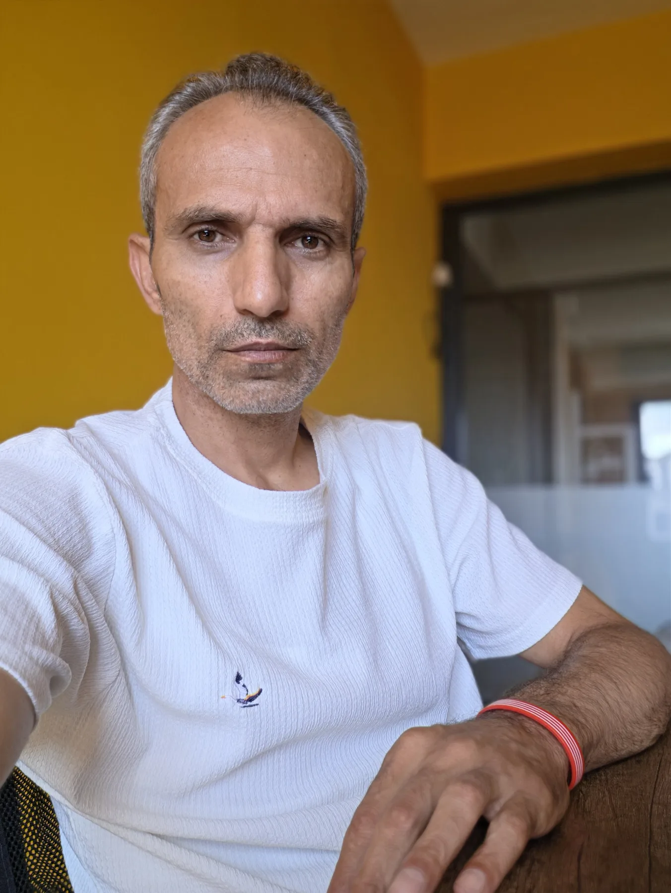 Galip Arduç’un ofis atmosferinde beyaz tişörtle otururken çekilmiş rahat, doğal ve özgüvenli portre fotoğrafı.