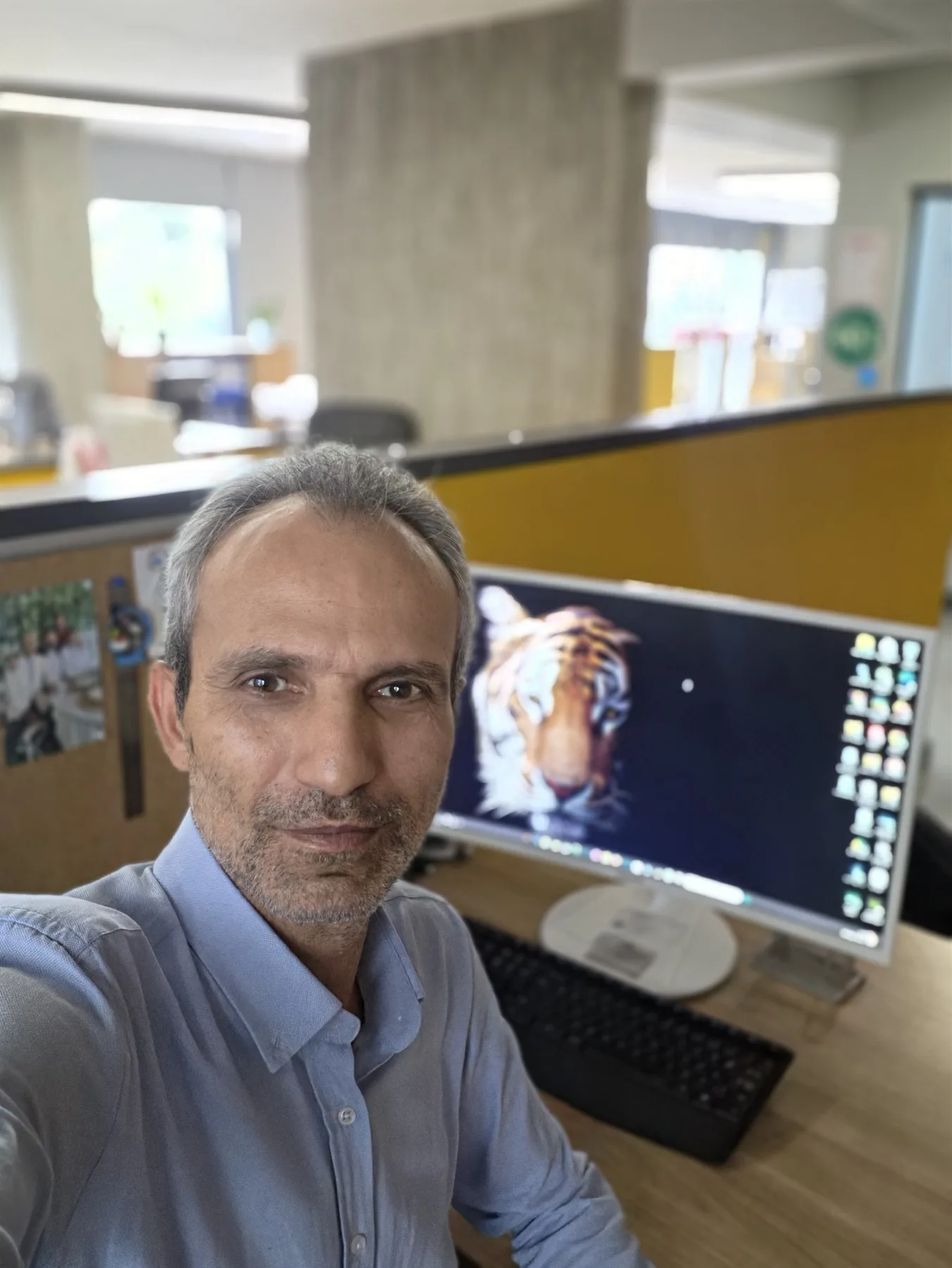 Galip Arduç’un modern ofisinde bilgisayar masası önünde açık mavi gömlekle çekilmiş doğal ve samimi çalışma portresi.