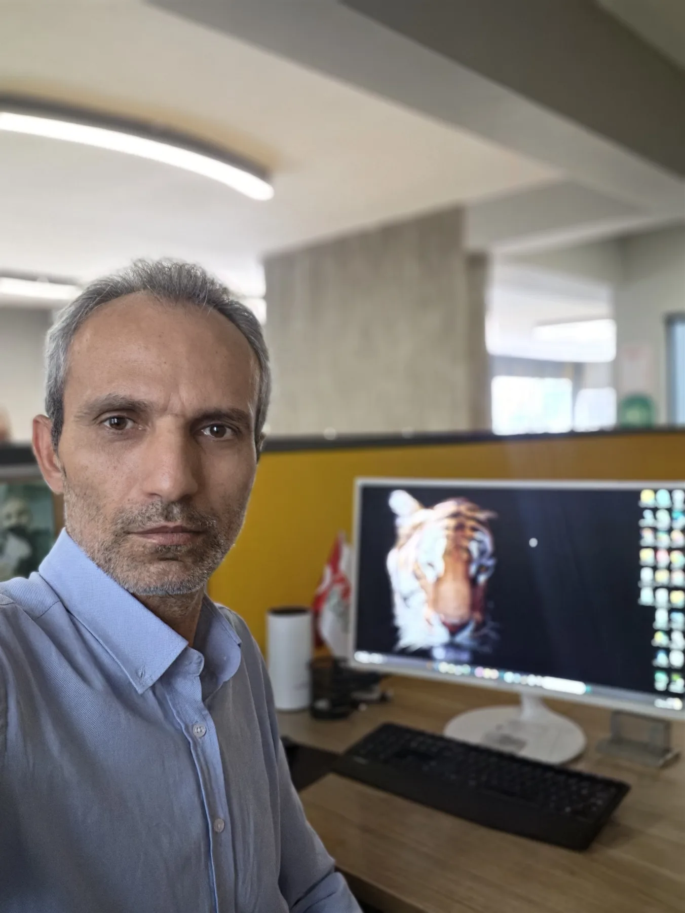 Galip Arduç’un modern çalışma ortamında bilgisayar başında, açık mavi gömlekle çekilmiş profesyonel ofis portresi.