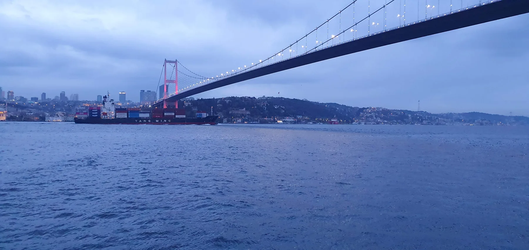 Galip Arduç’un İstanbul Boğazı ve Boğaziçi Köprüsü manzarasını gün batımına yakın saatlerde yansıtan şehir fotoğrafı.
